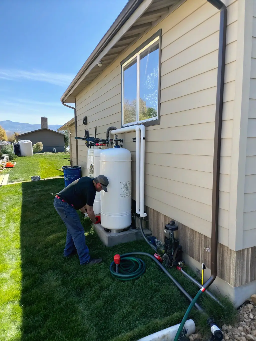 A Weiliya technician performing routine maintenance on a water treatment system in a residential setting, checking filters and system performance.
